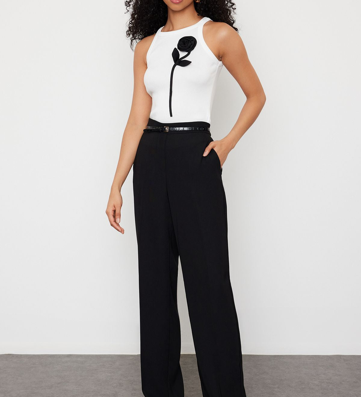 Shop our white ribbed tank top featuring a chic black floral appliqué. Ideal for casual or formal occasions, adding style and sophistication to your wardrobe.